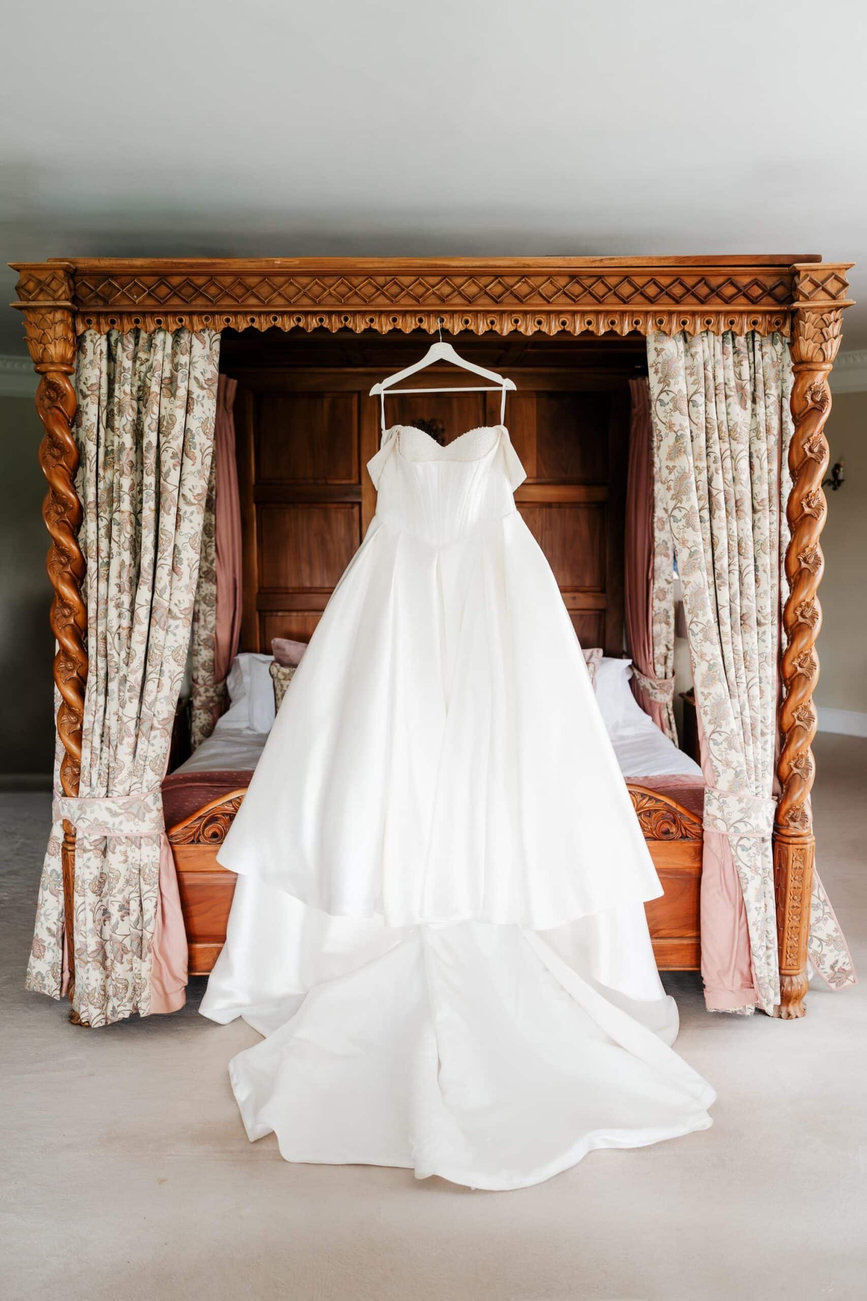 Wedding dress hanging on a four poster bed at Goldsborough Hall wedding venue