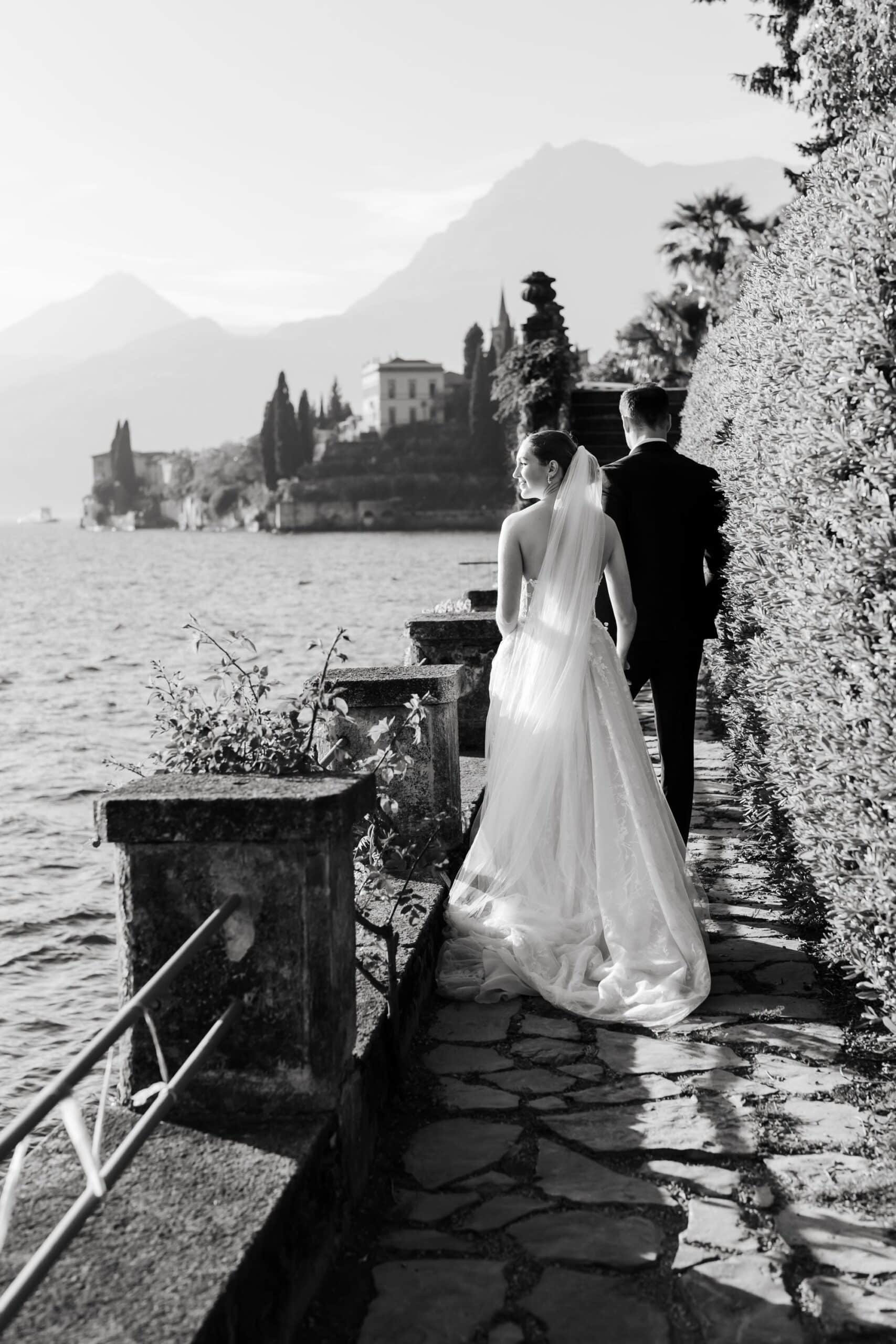 Bride and groom walking along the lakeside path at Villa Monastero