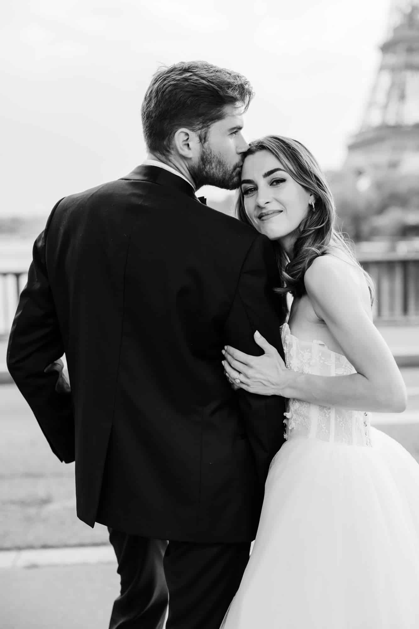 Bride and groom embracing on Pont de Bir-Hakeim with the Eiffel Tower