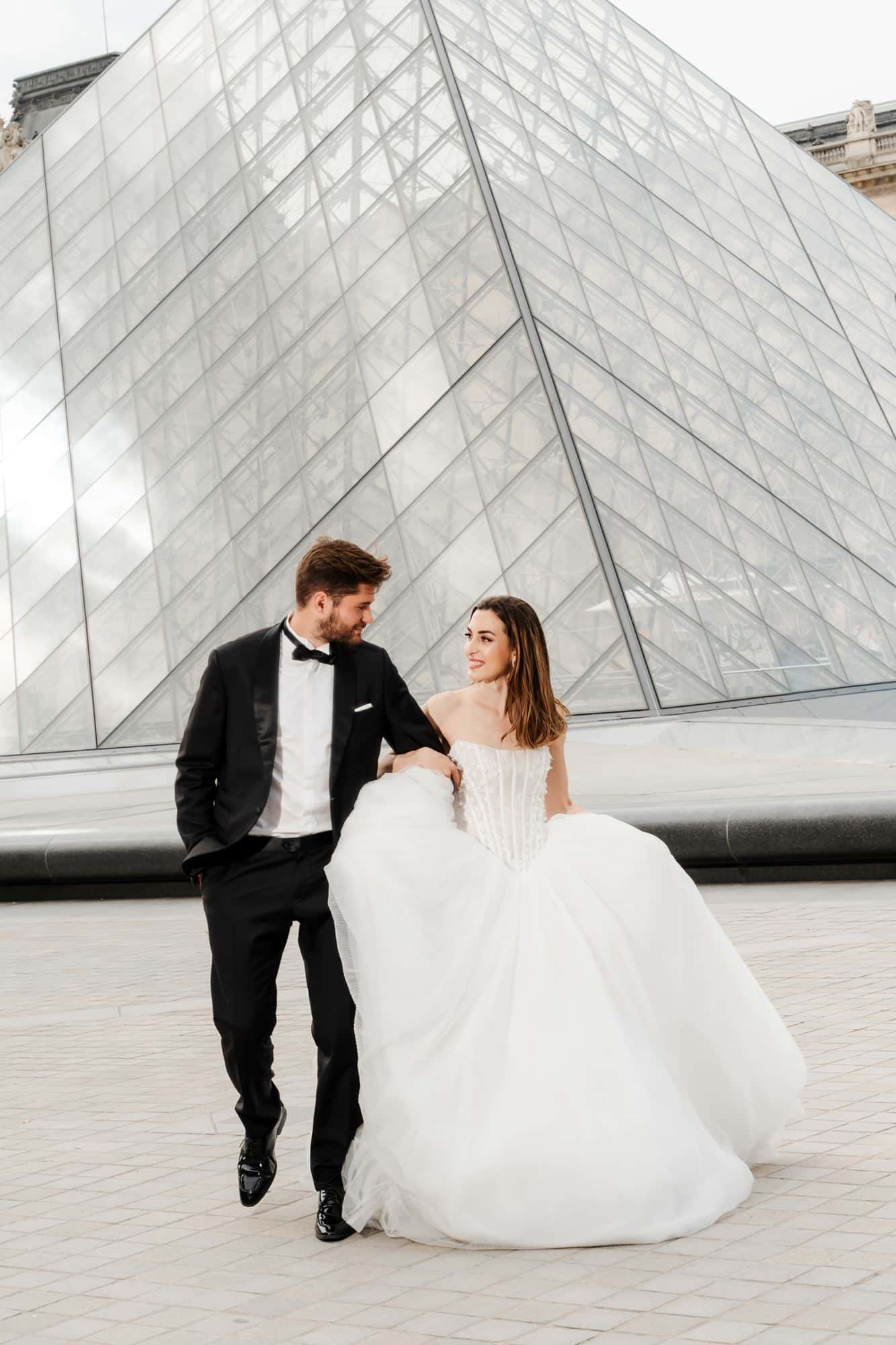Bride and groom with a wide view of the Louvre Pyramid, Paris